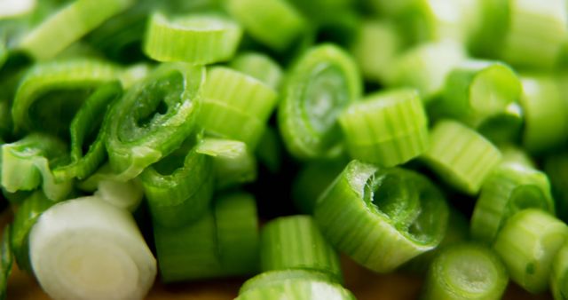 Freshly chopped green onions are scattered across a surface, offering a vibrant look at the popular culinary garnish. Green onions, also known as scallions, are a staple in various cuisines for their mild flavor and crisp texture.
