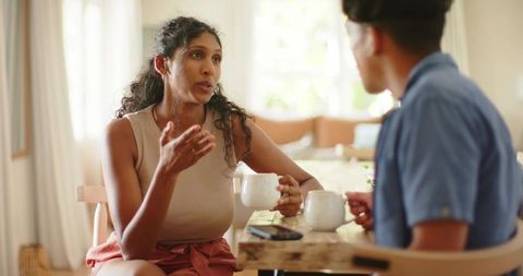 Sunlit conversation over coffee between african couple at cozy wooden dining table