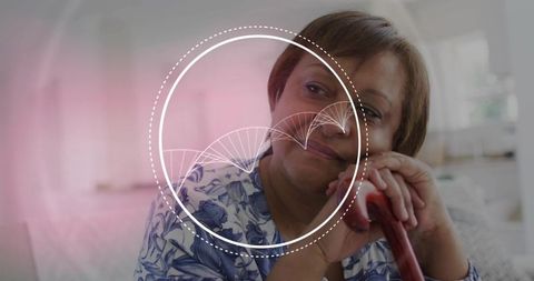 Mature woman leaning on cane, resting and reflecting in home wearing floral blouse