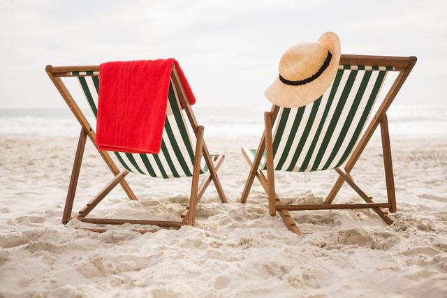 Straw hat and towel kept on beach chairs at tropical sand beach