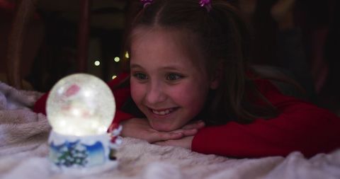 Joyful Girl Enjoying Snow Globe Magic at Christmas