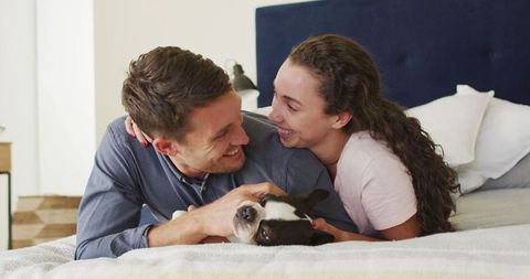 Happy Couple Relaxing with Dog in Cozy Bedroom