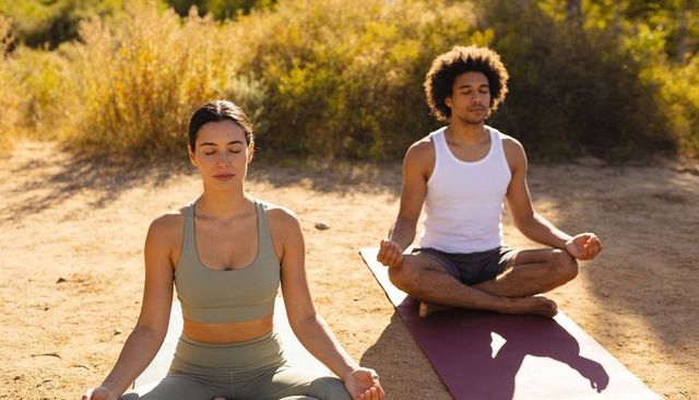 Couple meditating outdoors on yoga mats at golden hour practicing mindfulness and breathwork