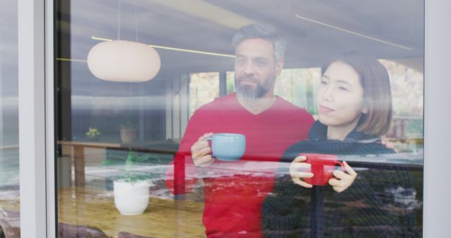 Happy diverse couple drinking coffee and talking together at home - Download Free Stock Photos Pikwizard.com
