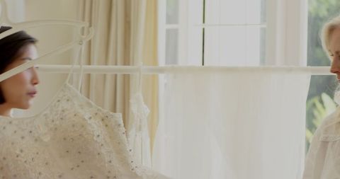 Bride Choosing Wedding Dress by Sunlit Window
