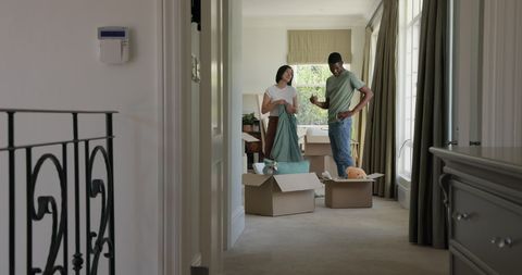 Couple unpacking moving boxes in new home and discussing decor