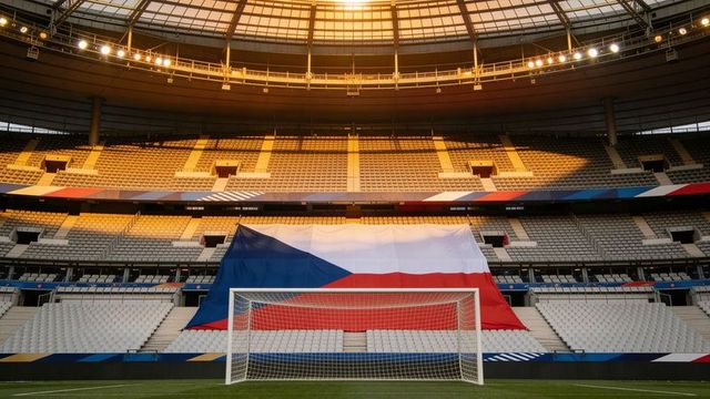 Czech republic flag draping stadium seats behind goal, golden roof light glowing
