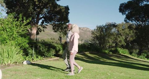 Active senior couple enjoying leisure walk in lush garden