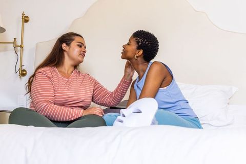 African american couple sharing gentle skincare ritual on bed with led facial mask