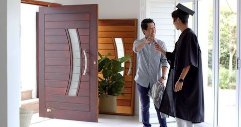 Proud father congratulating graduating son at home entrance