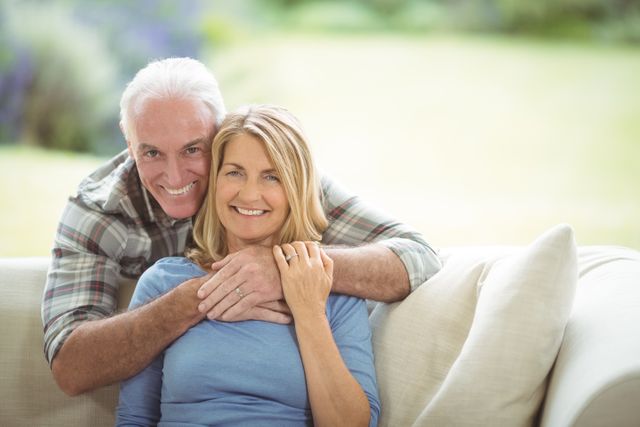 Portrait of smiling senior man embracing a woman in living room at home
