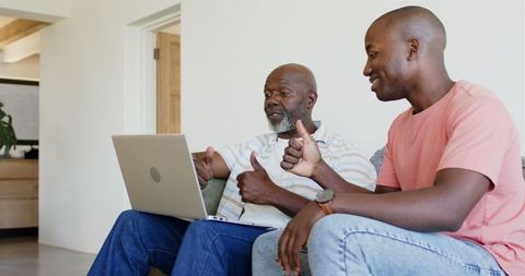 Father and Son Bonding Over Laptop with Thumbs Up Gesture