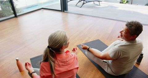 Diverse Mature Couple Meditating on Yoga Mats at Home