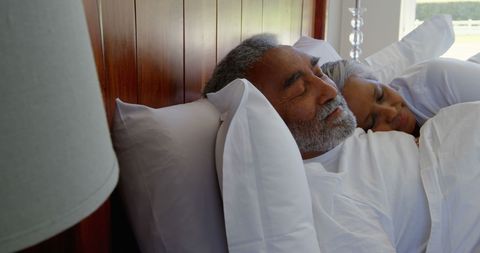 Senior Mixed Race Couple Relaxing Peacefully in Bed During Daytime