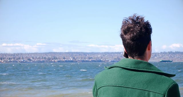 Man in Green Coat Looking at Ocean from Shoreline - Download Free Stock Images Pikwizard.com