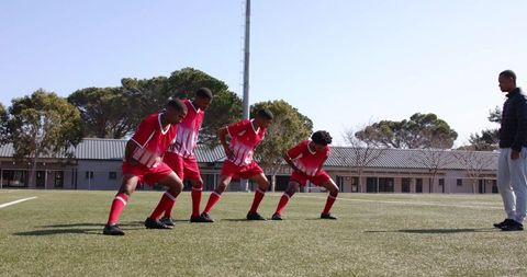 Youth soccer players warming up with coach guidance on field
