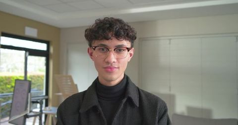 Young professional mid twenties standing in modern office lounge wearing round eyeglasses