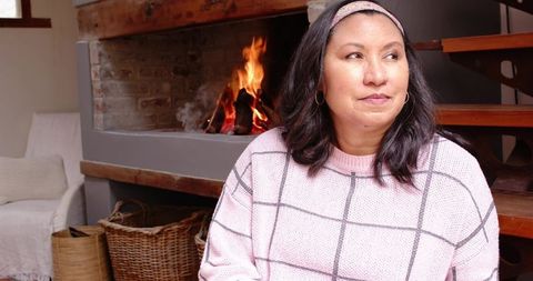 Middle-aged woman by fireplace in cozy home interior