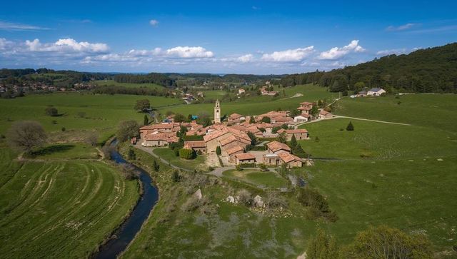 Village cluster sitting in rolling green countryside with bell tower and terracotta roofs
