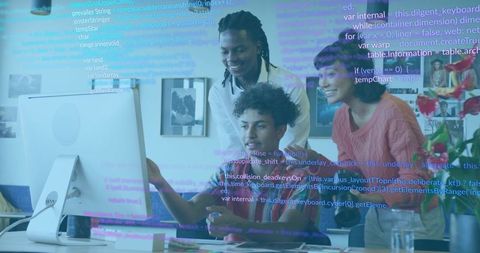 Diverse young developers collaborating at desktop with code overlay and friendly teamwork