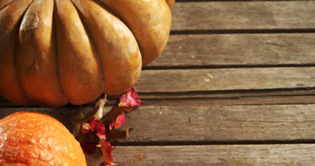 Rustic autumnal pumpkins with dry leaves on a weathered wooden background. Perfect for seasonal themes, fall decor, Thanksgiving promotions, or harvest festival advertisements.