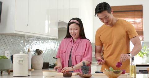 Asian Couple Preparing Healthy Dinner Chopping Vegetables Smiling in Bright Modern Kitchen
