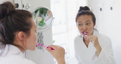 woman brushing teeth in bathroom mirror - Download Free Stock Images Pikwizard.com