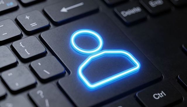 Glowing neon-blue user icon key on black keyboard representing digital identity