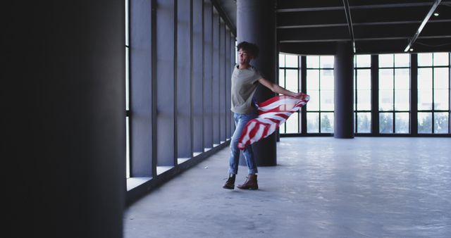 Young Person Joyfully Holding a Striped Fabric in a Spacious Empty Building - Download Free Stock Images Pikwizard.com