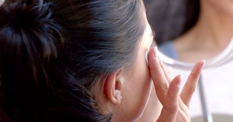 Scene captures teenage girl in casual setting engaging in self-care practice applying under eye masks using mirror. Focus is on beauty and health routine. Useful for articles on skincare tips for youths, promotional materials for beauty products, or wellness blogs promoting self-care habits.