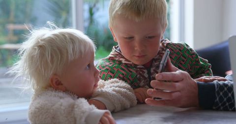 Curious Siblings Watching on Smartphone at Home