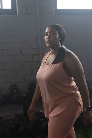 African american woman working out in industrial gym wearing pink activewear, focused