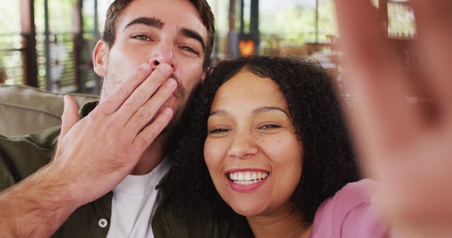 The image shows two joyful people, one blowing a kiss towards the camera while the other smiles widely. Ideal for use in romantic greeting cards, social media posts, relationship blogs, or advertisements promoting happiness and love.