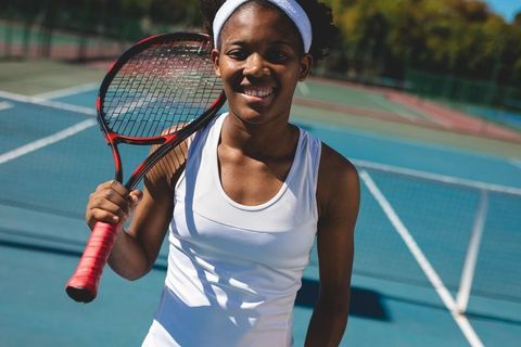 Confident female tennis player smiling on outdoor court