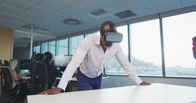 African american businessman using vr headset, with colleagues using computers at office - Download Free Stock Photos Pikwizard.com