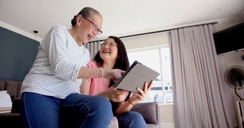Smiling Asian Mother and Daughter Bonding with Tablet at Home