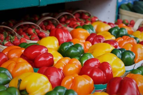 Colorful Bell Peppers Display with Fresh Strawberries at Farmers Market