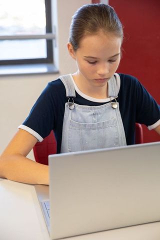 Teen student focusing on laptop in modern classroom environment