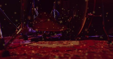 Drummer foot pressing kick pedal on red stage rug with warm bokeh and hardware