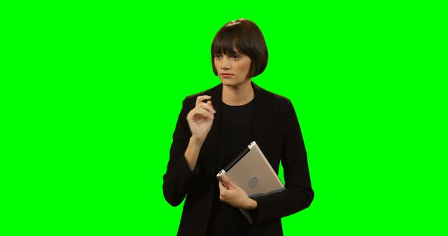 Woman dressed in black holding a tablet against green screen background. Ideal for use in business promotions, technology ads, or as an isolated element in demos and presentations.
