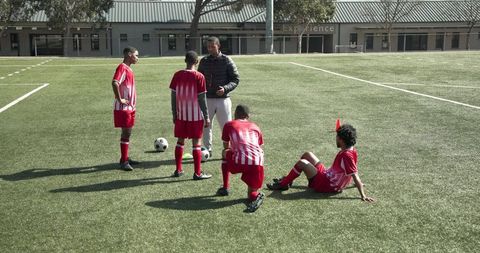 Soccer Coach Instructing Youth Team on Sunny Field