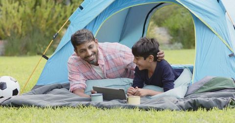 Happy Father and Son Enjoying Tablet in Camping Tent