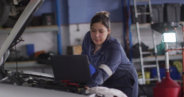Female mechanic using laptop and inspecting the car at a car service station. automobile repair service