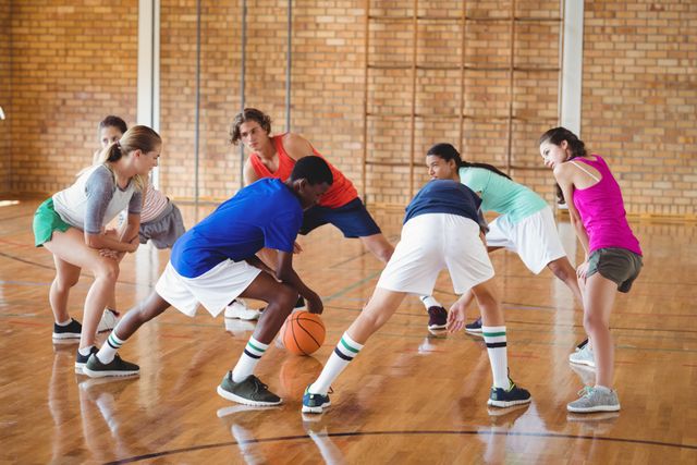 High school students warming up on a basketball court, preparing for a game. Ideal for use in educational materials, sports training guides, youth fitness programs, and teamwork promotion.