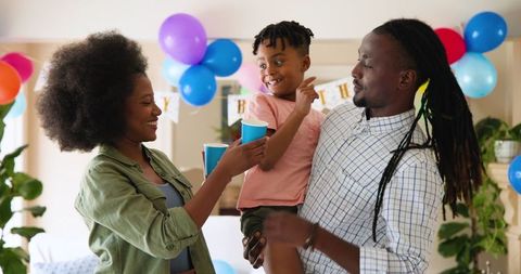 Joyful Family Celebrating Child's Birthday at Home with Balloons