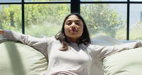 African american woman relaxing on sofa in sunlit minimalist living room