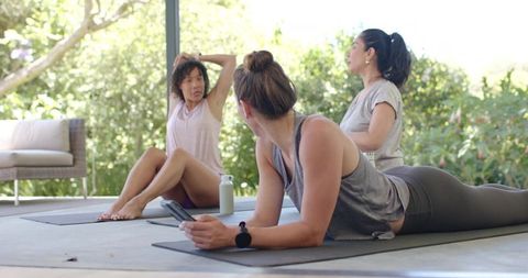 Diverse women practicing outdoor yoga on patio, friends stretching in athleisure wellness