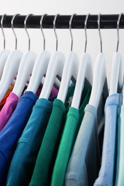 This image shows a close-up view of colorful t-shirts neatly arranged on a clothing rack. It is ideal for use in fashion blogs, retail advertisements, wardrobe organization tips, and online clothing stores to showcase a variety of casual wear options.