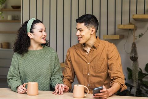 Young couple holding hands over coffee in cozy kitchen sharing warm morning conversation