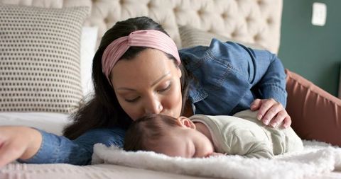 Mother tenderly kissing sleeping baby in cozy bedroom